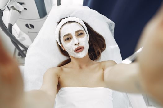 A woman enjoys a relaxing spa facial treatment with a moisturizing mask indoors. Perfect for wellness and skincare concepts.