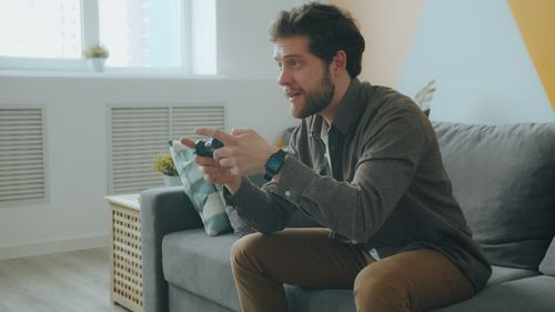 Free A man focused on playing video games on a console in a modern living room setting. Stock Photo