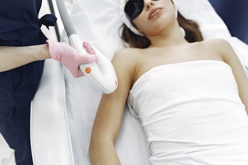 From above of unrecognizable cosmetologist in uniform and latex gloves using modern equipment for cosmetic services in contemporary salon