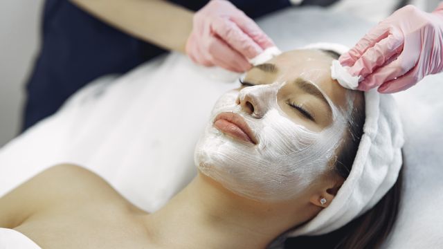 Profissional de estética preparando produtos para sessão de limpeza de pele em clínica especializada.