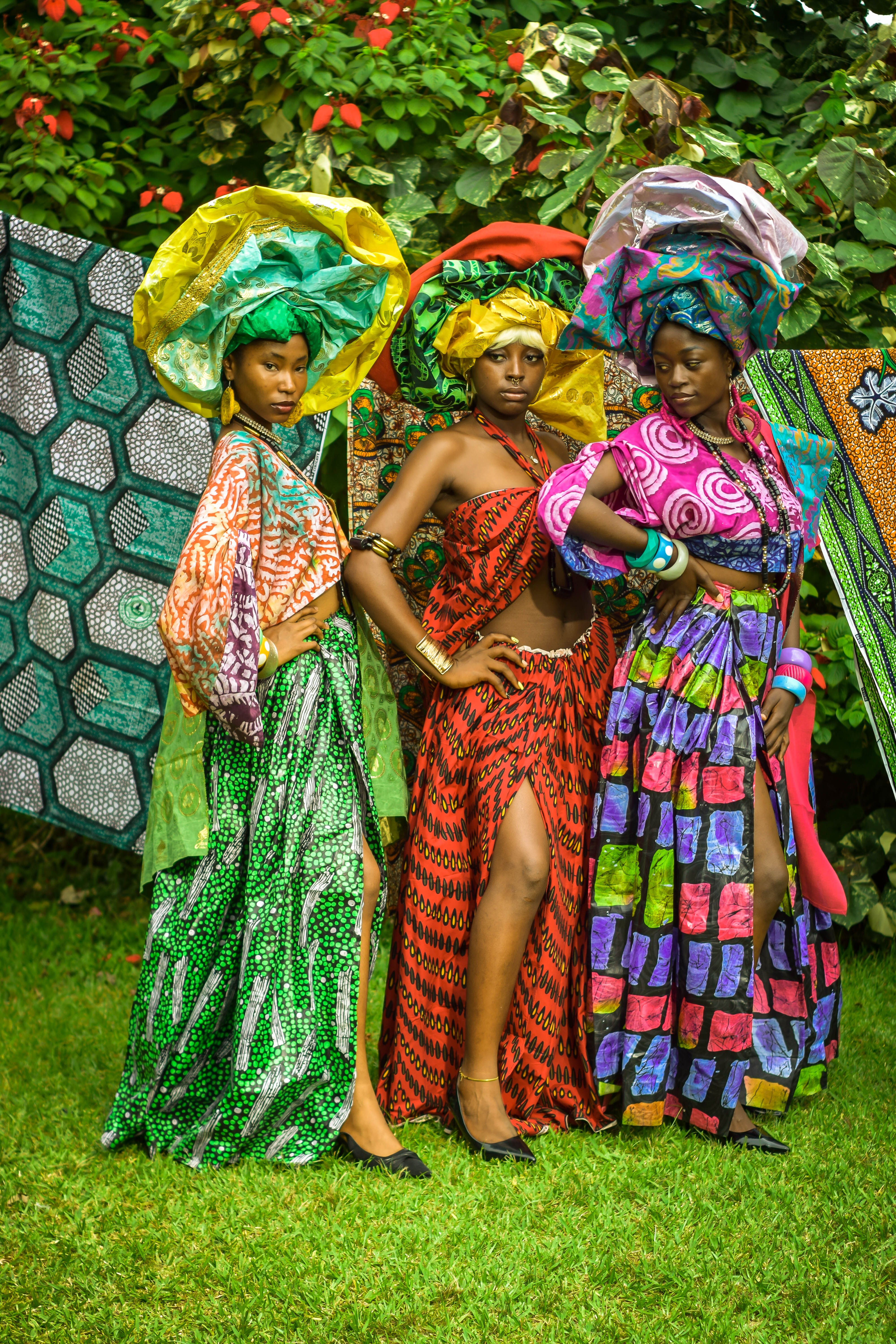 Fotomural Tres mujeres con coloridos atuendos africanos posan al aire libre mostrando la moda tradicional.