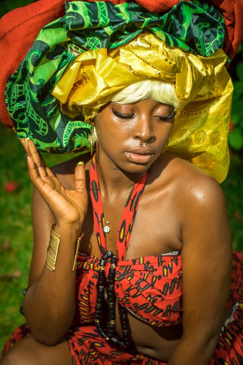 Free A colorful portrait of a woman in traditional attire with vibrant headwrap outdoors. Stock Photo