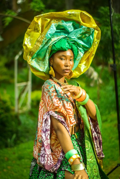 Free A woman wearing vibrant traditional African attire with bold accessories in a lush outdoor setting. Stock Photo