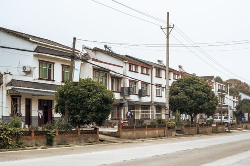 Free A quiet suburban street lined with a row of houses and greenery, ideal for daily life scenes. Stock Photo