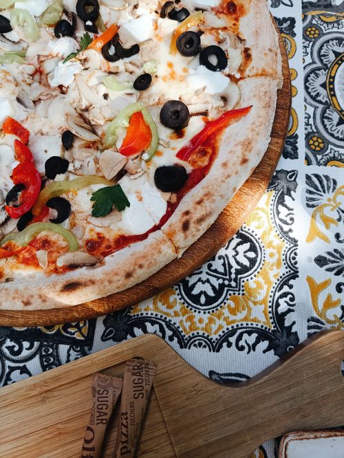 Free Close-up of a homemade pizza with colorful toppings on a patterned tablecloth, perfect for Italian cuisine lovers. Stock Photo