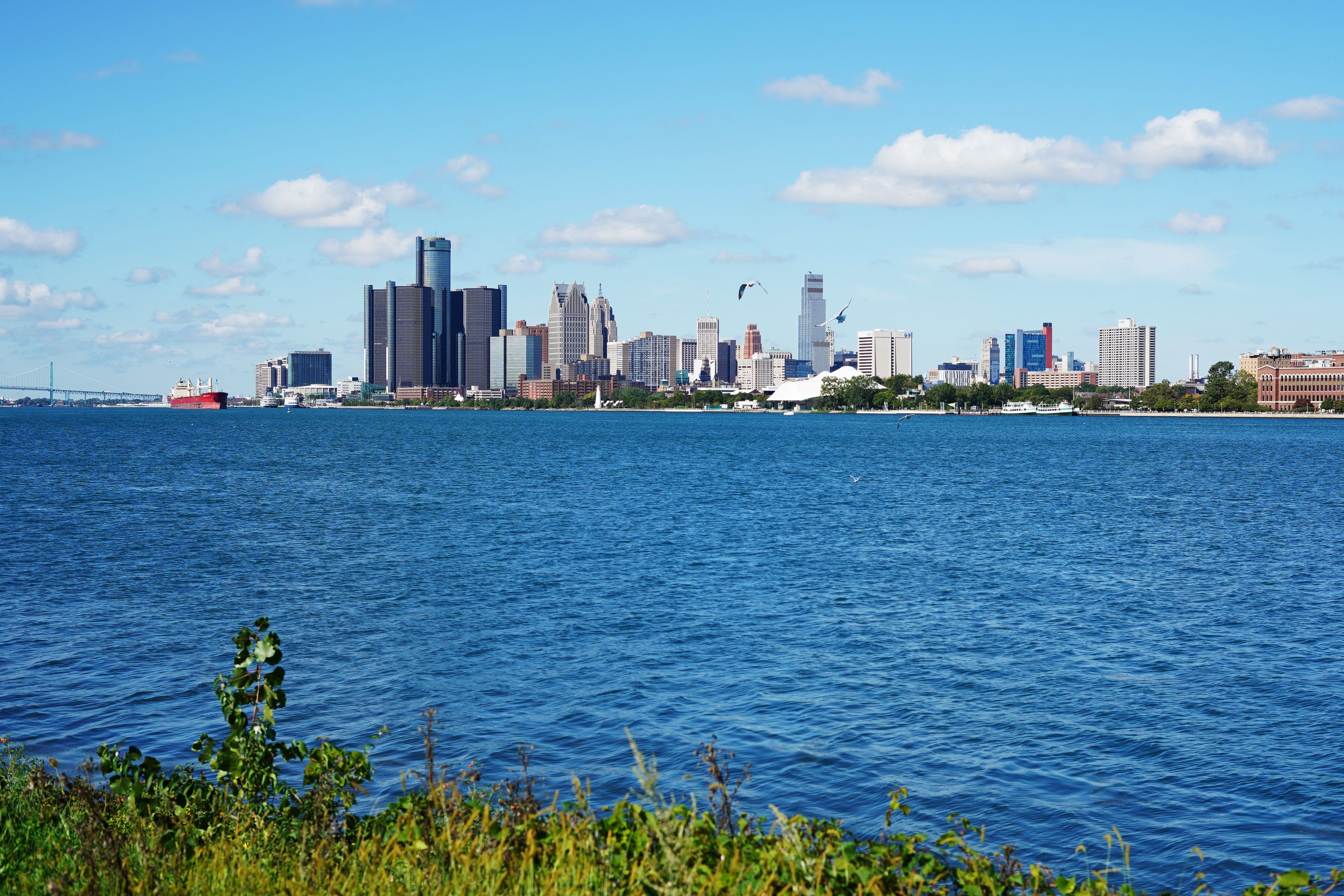 Stunning view of Detroit skyline with clear blue skies and tranquil river.