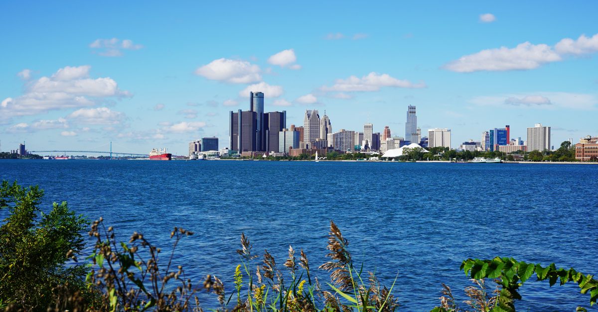 Stunning view of the Detroit skyline across the blue waters of the Detroit River under a clear sky.