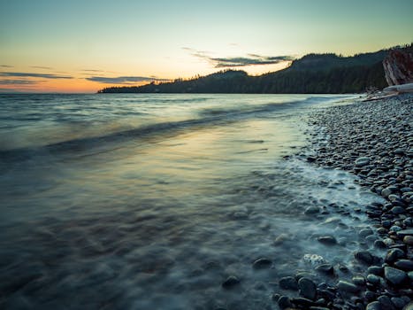 Tranquil sunset over a pebbled shoreline in British Columbia, Canada, capturing the coast's serene beauty.