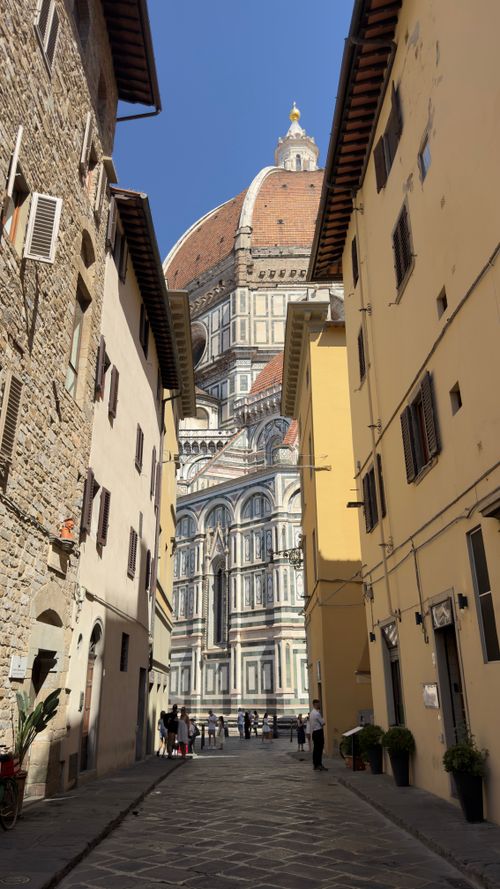 Free Historic view of Florence Cathedral's dome through a narrow street in Florence, Italy. Iconic Renaissance architecture. Stock Photo