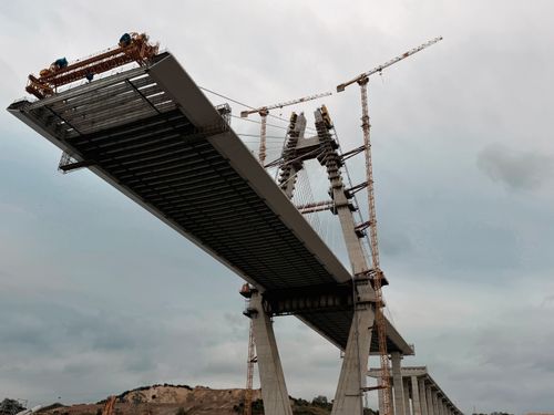 Free A partially-built bridge with cranes highlights modern engineering. Stock Photo