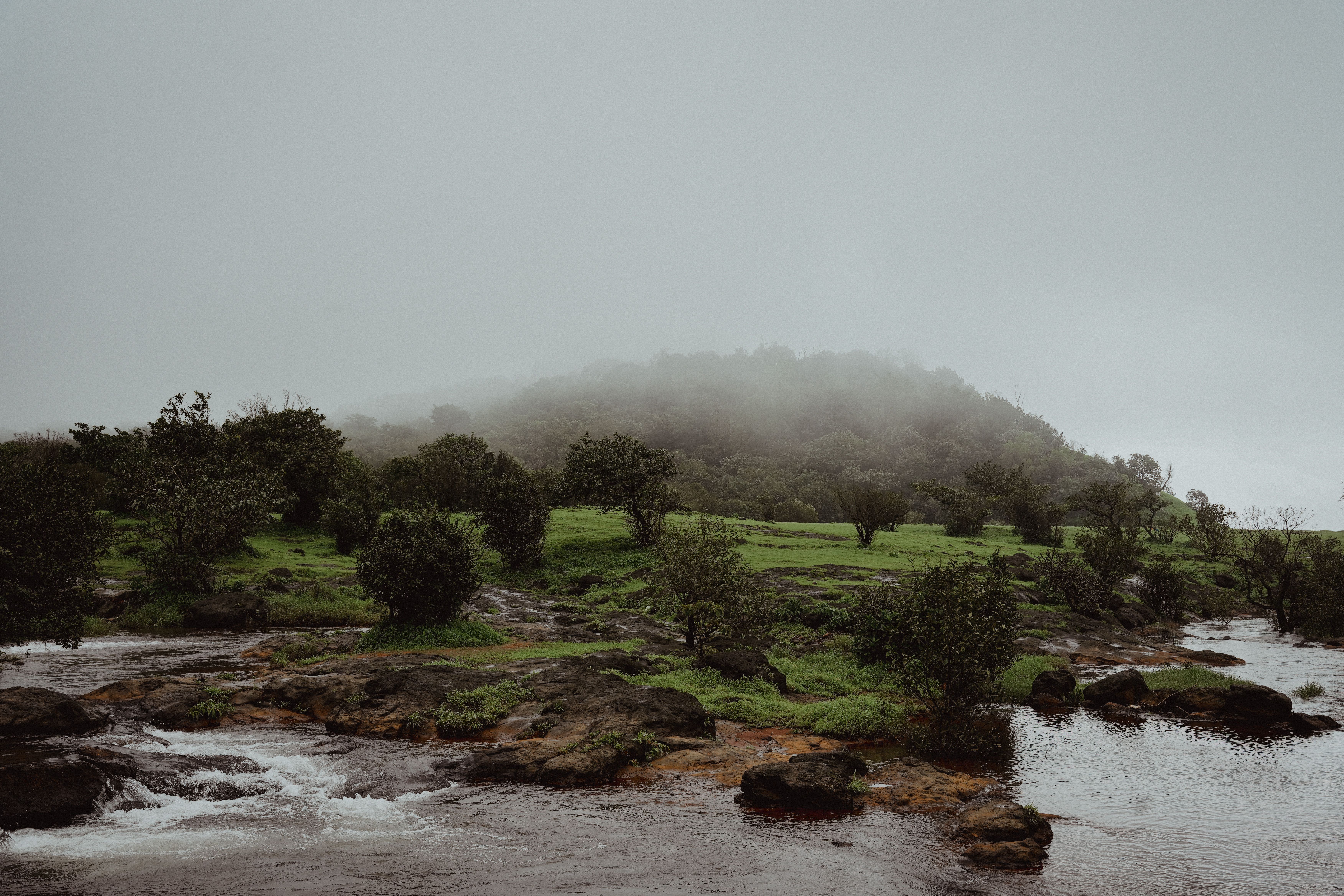 Serene misty landscape featuring a flowing river and lush green hills.