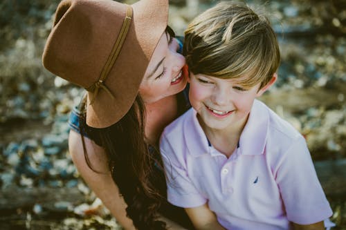 Woman In Brown Hat Smiling Beside Boy In Polo Shirt