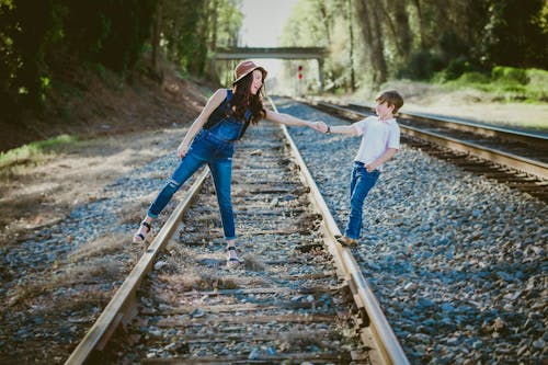 Free Woman In Blue Denim Dungarees And Black Tank Top Holding Hands With A Boy Stock Photo
