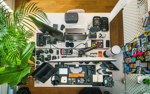 Free Top view of a well-organized home studio workspace featuring photography equipment, camera gear, and editing tools. Stock Photo