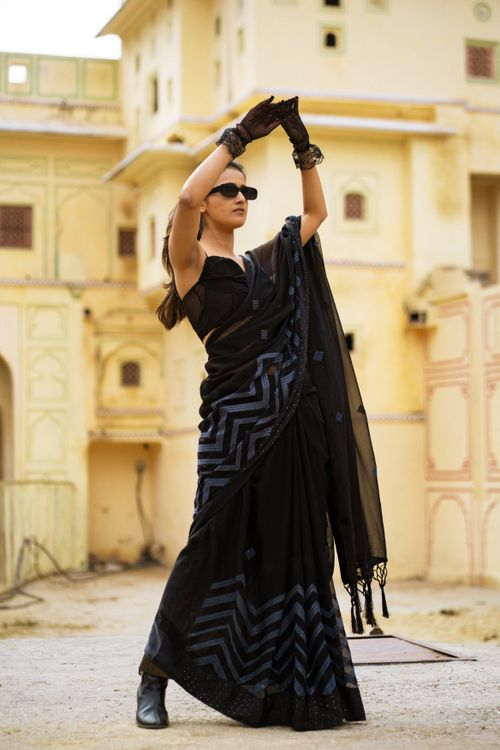 Free Woman in traditional black saree dances gracefully in historic outdoor setting, showcasing cultural elegance. Stock Photo