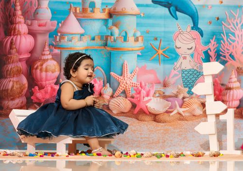 Free Charming baby girl in a vibrant mermaid-themed backdrop with sea shells and castles. Stock Photo