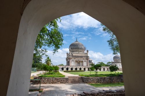 Free A stunning view of Qutb Shahi Tombs framed by an arch in Hyderabad, India, on a bright summer day. Stock Photo