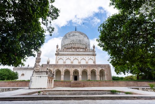 Free Majestic view of Qutb Shahi Tomb surrounded by lush greenery with a clear blue sky in Hyderabad, India. Stock Photo