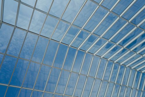 Free A striking view of a modern glass roof with a clear blue sky backdrop. Stock Photo
