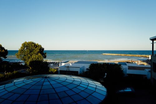 Free Scenic view from a hotel balcony overlooking a calm blue sea and sandy beach. Stock Photo