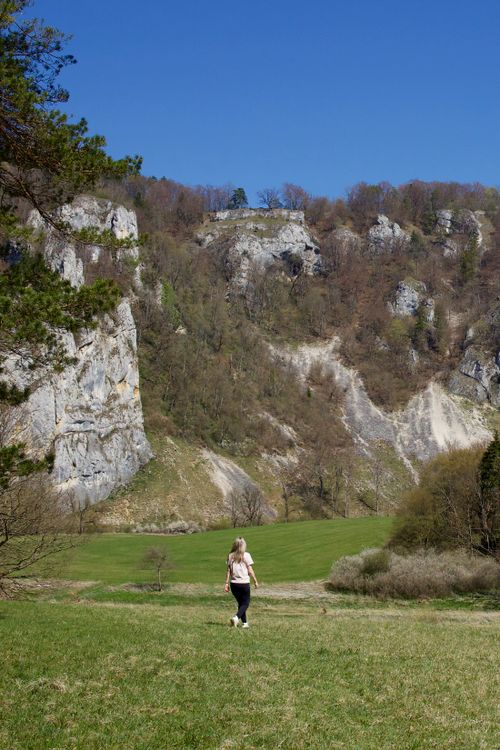 Free A lone hiker walks through the lush landscape of Beuron, Germany, under a clear blue sky. Stock Photo