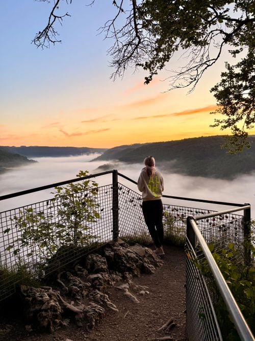 Free A lone person stands at a scenic overlook, watching sunrise over a fog-filled valley, capturing serenity and introspection. Stock Photo