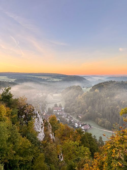 Free A breathtaking view of Lautertal valley at sunrise, showcasing misty forests and quaint village houses. Stock Photo