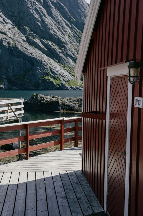 Free Traditional red cabin by the fjord in Nusfjord, Norway showcasing stunning natural landscape. Stock Photo