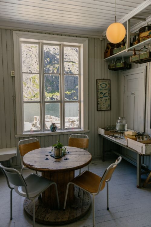 Free Charming Scandinavian-style room overlooking a serene Norwegian fjord through large windows. Stock Photo