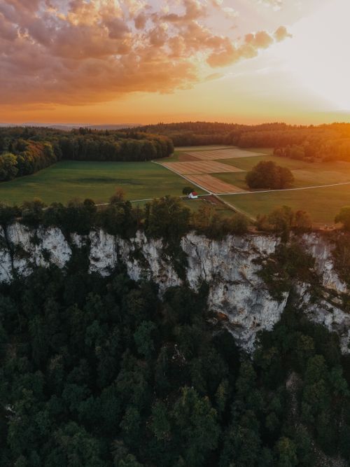 Free Stunning aerial view of Sankt Johann's cliffs and farmland under a dramatic sunset sky. Stock Photo