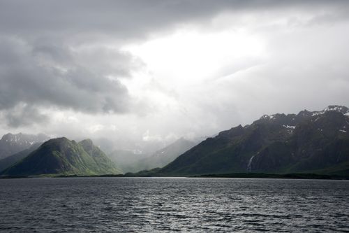 Free A breathtaking view of Nordland's rugged coastline, featuring lush green mountains under dramatic skies. Stock Photo