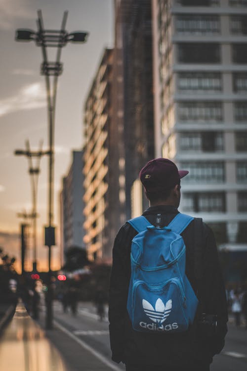 Personne Portant Un Sac à Dos Adidas Bleu Debout Près Des Bâtiments