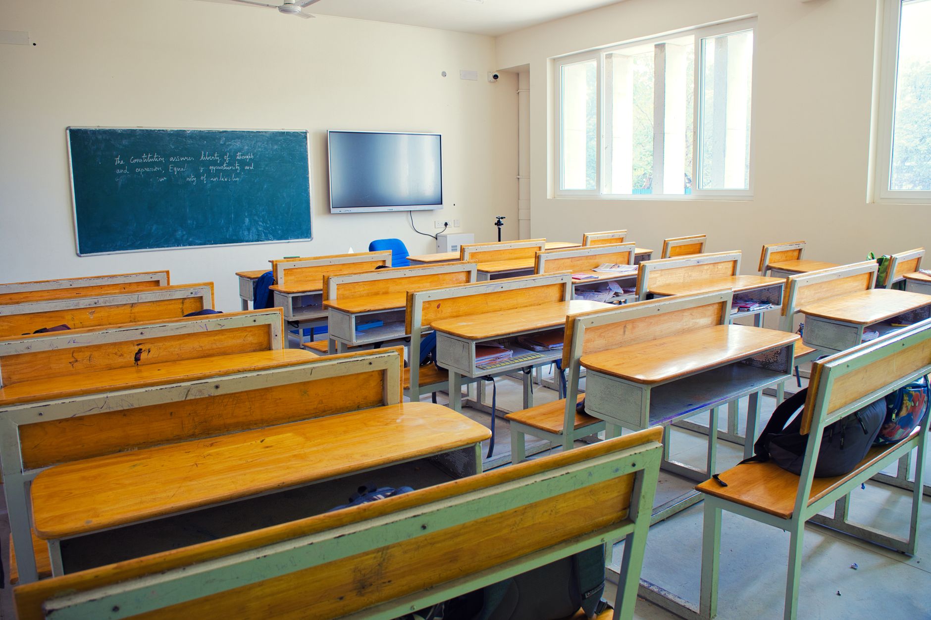 Bright classroom in Chennai with wooden desks, blackboard, and modern screen.