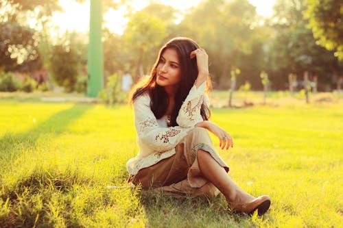 Woman In White Top Sitting On Green Grass Field