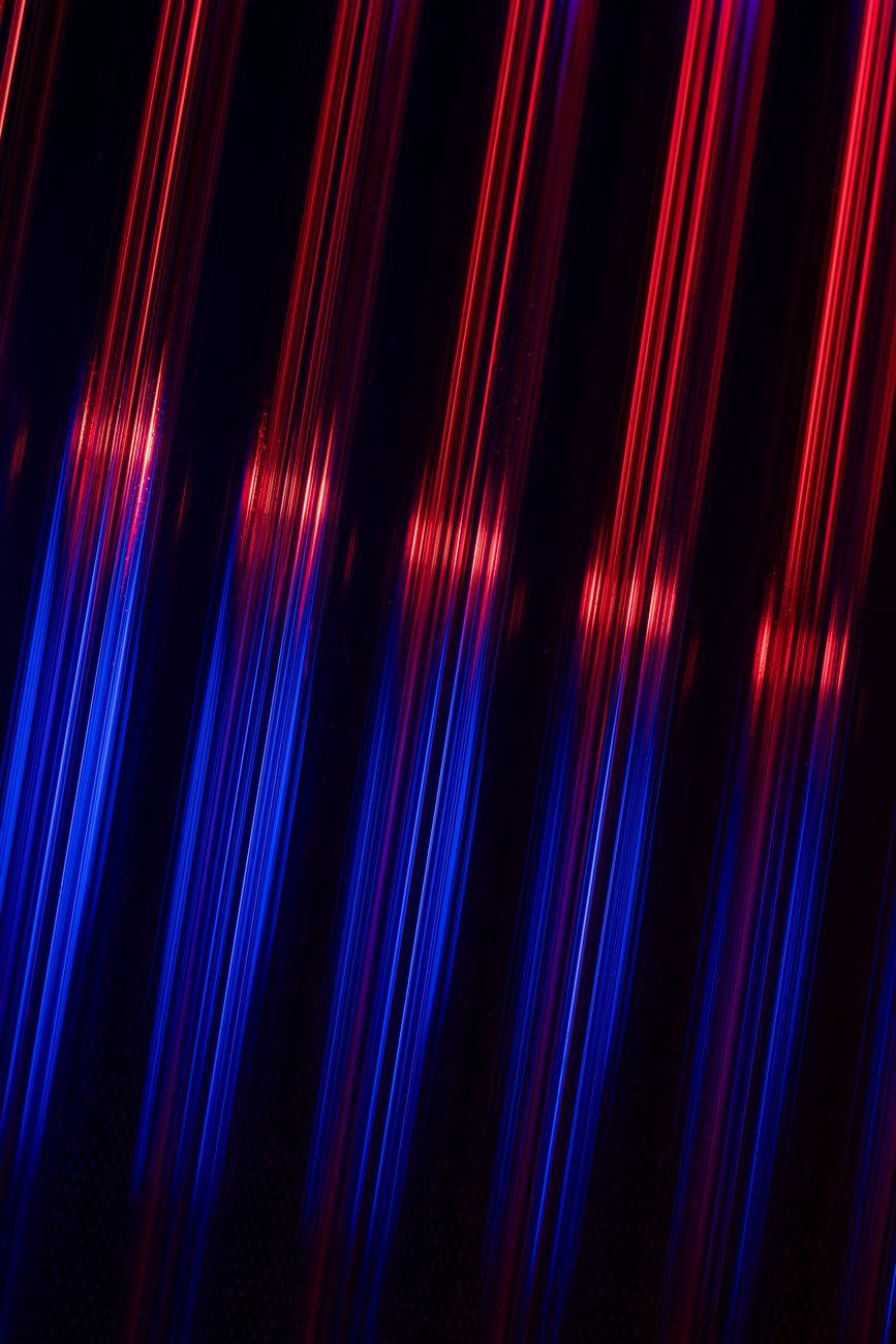 A vivid abstract display of neon red and blue light reflections with a futuristic feel.