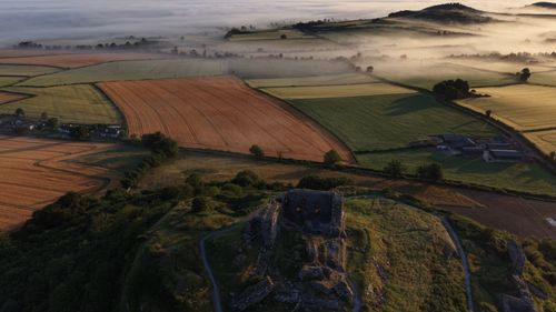 Free Aerial shot of scenic countryside fields at sunrise, with mist and ancient ruins. Stock Photo