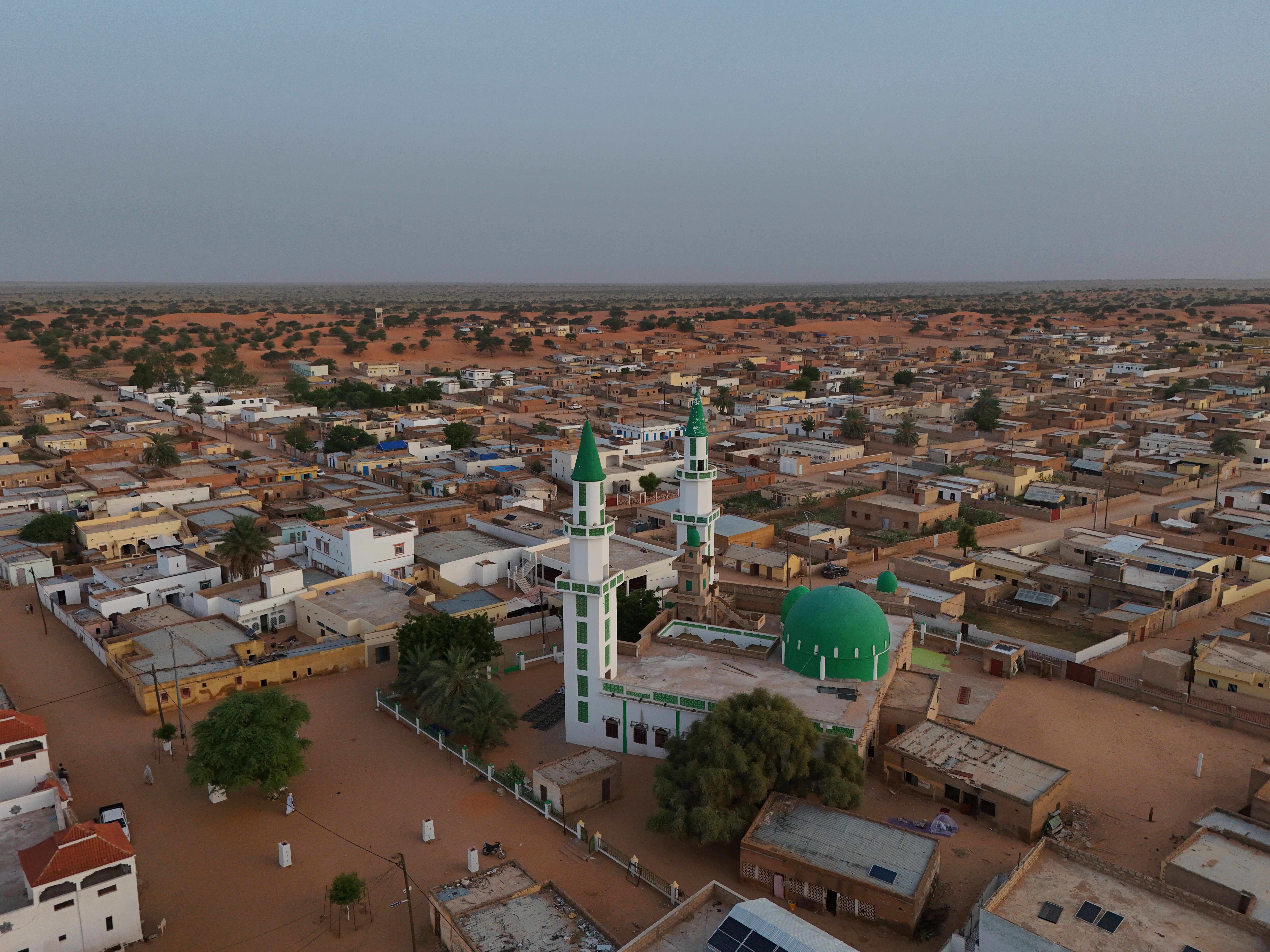 Aerial shot of an Islamic mosque with green domes in a Mauritanian village.