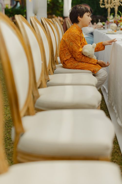 Free A child in traditional clothing sits thoughtfully at a set table outdoors. Candid and serene atmosphere. Stock Photo