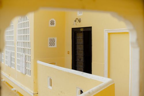 Free Elegant architecture featuring a yellow facade with decorative arched windows and a classic wooden door. Stock Photo