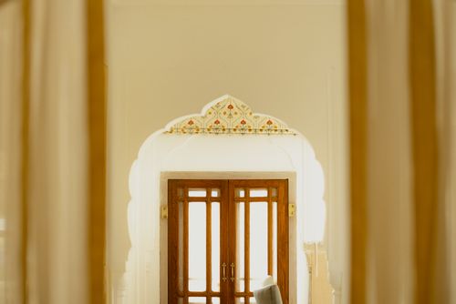Free A beautifully designed wooden door with intricate archway details in a traditional setting. Stock Photo