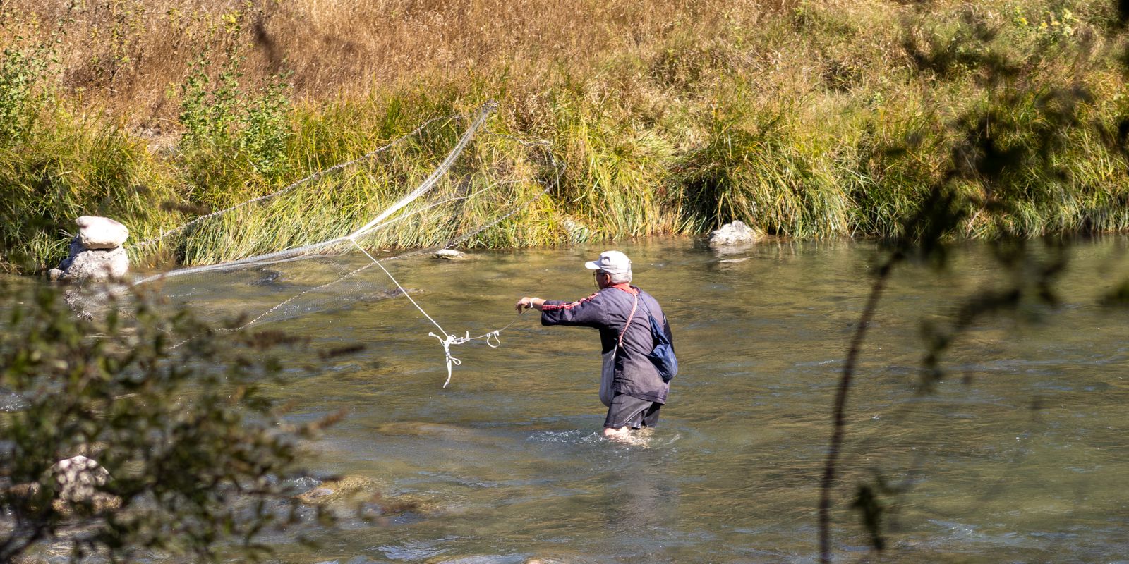A fly fisherman casting in a serene mountain river