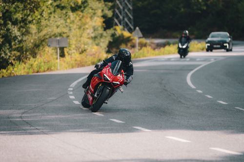 Free Motorcyclist leaning into a turn on a winding road, showcasing speed and precision. Stock Photo