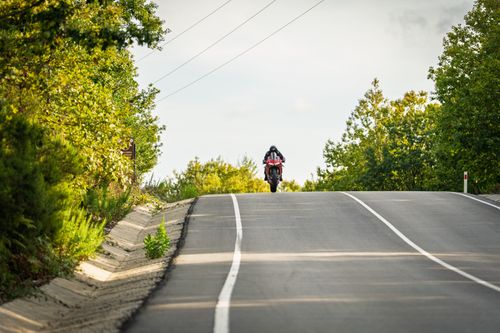 Free A motorcyclist rides on a scenic road through lush greenery, perfect for adventure enthusiasts. Stock Photo