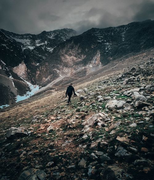 Free Solo hiker exploring rugged mountainous terrain on a cloudy day, capturing nature's raw beauty. Stock Photo
