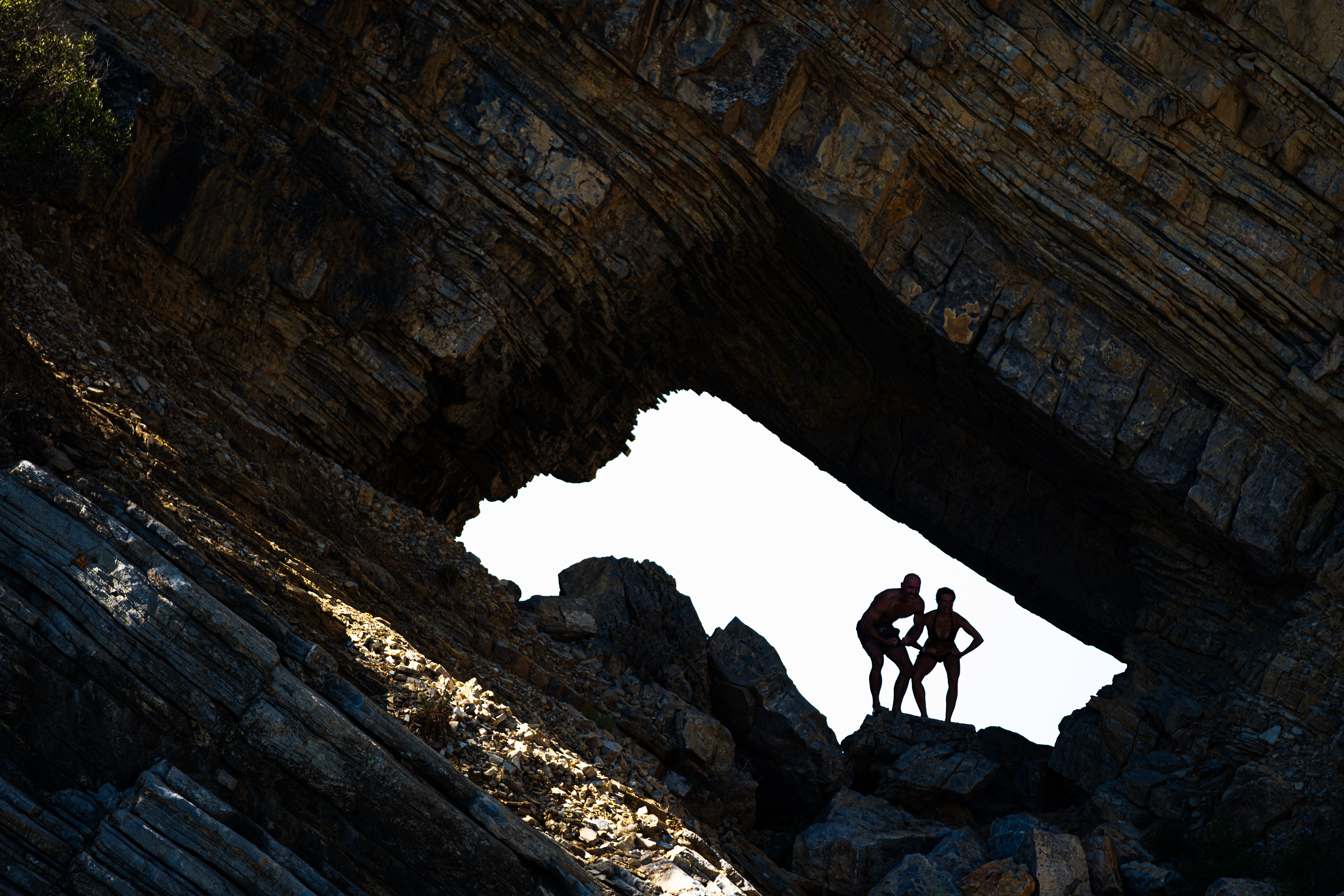 Two people silhouetted in a dramatic rock formation in Muğla, Türkiye.