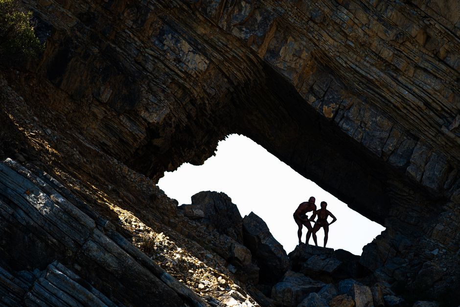 Two people silhouetted in a dramatic rock formation in Muğla, Türkiye.