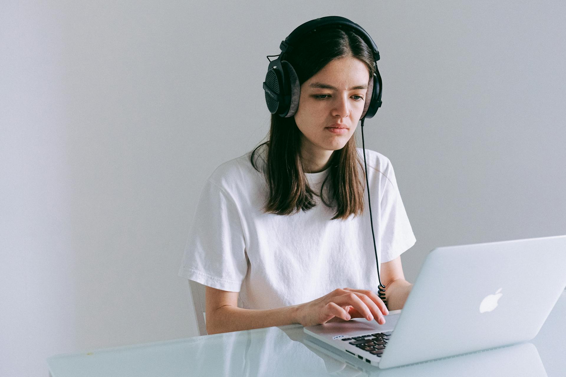 A woman in a home office working on her laptop with headphones. Perfect for representing remote work and technology.