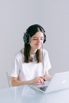 A woman enjoys remote work from home using a laptop and headphones.