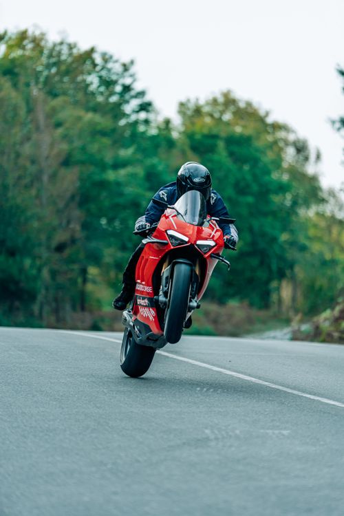 Free Thrilling motorcycle wheelie showcasing speed and agility on an open road. Stock Photo