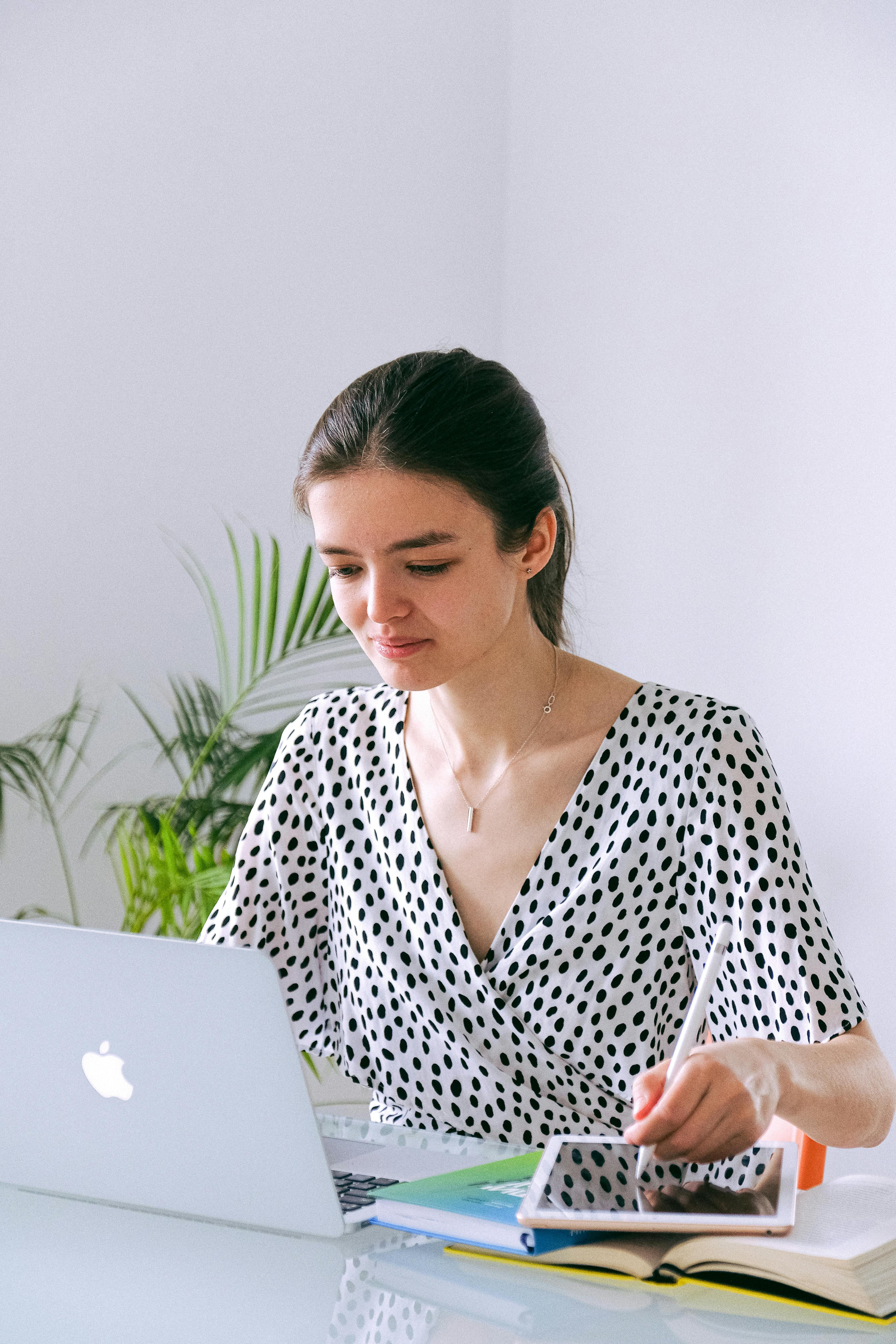 woman in black and white v neck clothing using silver macbook